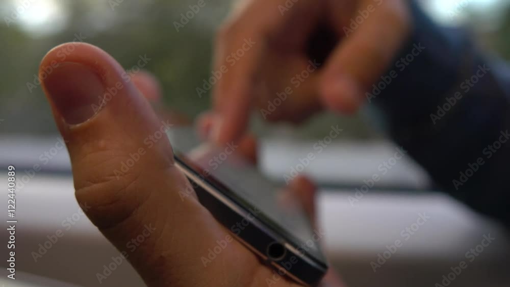 Aufkleber man using his telephone horizontally against the train window. scrolling and tapping on device touch