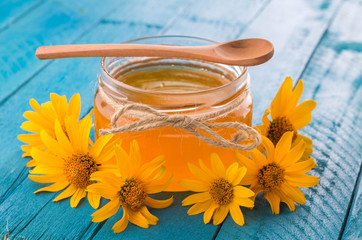 Honey in a glass jar with flowers