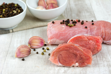 Raw pork meat with herbs on a wooden board.
