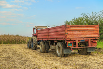 Tractor with trailer standing in a field waiting for harvest