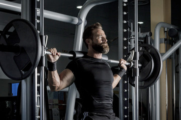 Hombre con grandes músculos levantando peso mientras entrena en el gimnasio. Ponerse en forma.