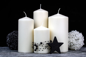 Vier weiße Kerzen mit schwarz weißer Dekoration auf silber