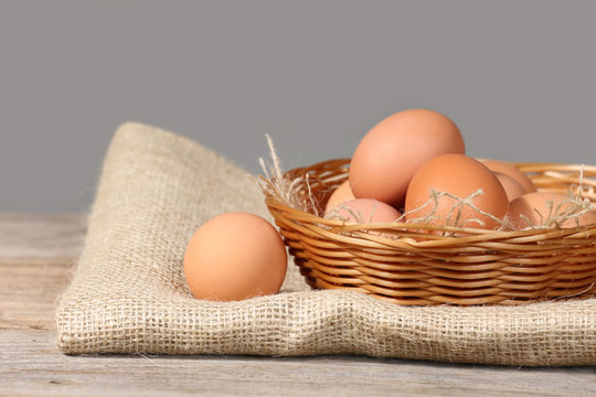 Brown eggs in basket lie on sackcloth over rough wooden table