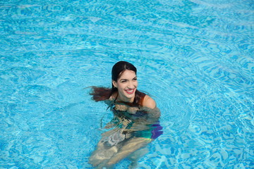 beautiful young woman relaxing in water by the swimming pool