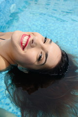 beautiful young woman relaxing in water by the swimming pool