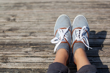 Woman feet in casual shoes on the wooden background