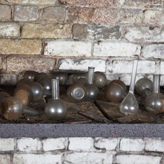 Flasks, old and dirty, in basement of abandoned chemical laboratory on brick wall square background