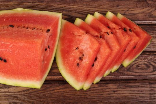 Watermelon quarter and slices on red toned wooden table
