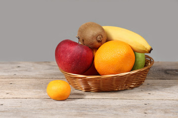 Set of different exotic tropical fruits in basket on wooden table