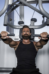 Hombre con grandes músculos levantando peso mientras entrena en el gimnasio. Ponerse en forma.