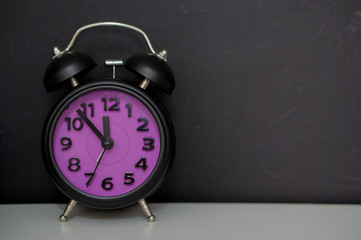 black and purple alarm clock with blackboard in the background