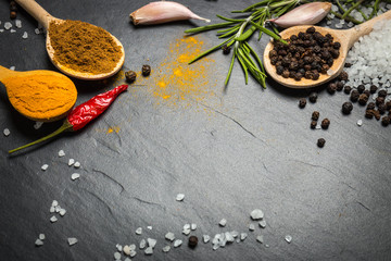 spices and herbs over black stone background, top view with copy space