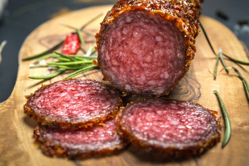 dried salami crusted in ground red pepper on dark background