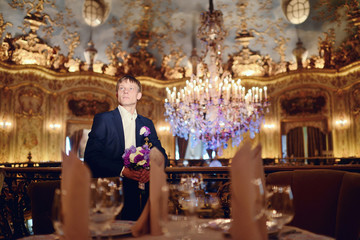 Handsome groom in suit in the hall. Male portrait in the room. Beautiful model boy in colorful wedding clothes. Man is posing. Handsome guy indoors