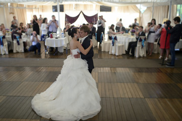 Wedding couple in the restaurant is dancing. Beautiful model girl in white dress. Handsome man in suit. Beauty bride with groom. Female and male portrait. Woman with lace veil. Lady and guy indoors