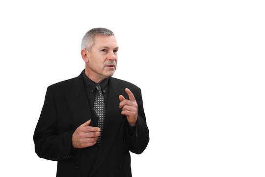 Middle Age Man In Business Black Suit Holds Mobile Phone In Hand And Speaks Gesturing Isolated On White Background