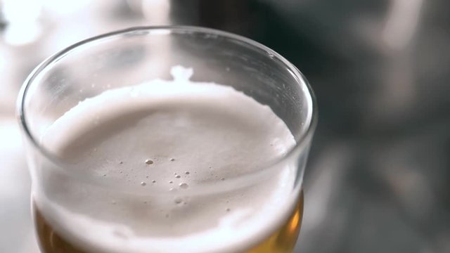 Beer into glass with a lot of bubles and foam super close up slow motion.