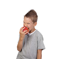 Joyful teenage boy aggressive bites off a big red apple in hand isolated on white background is square
