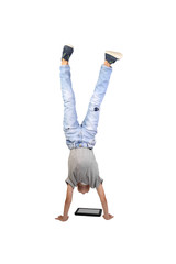 Teenage boy stands on hands and looks at the tablet on floor isolated on white background
