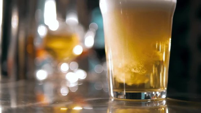Beer into glass with a lot of bubles and foam super close up slow motion.