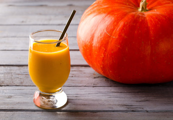 Healthy pumpkin smoothies with spices and nuts on rustic table
