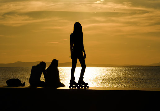  Teenage girl on roller skates at summer, silhouette. 