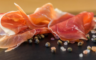 thin slices of prosciutto with mixed with basil on wooden cutting board,vintage background