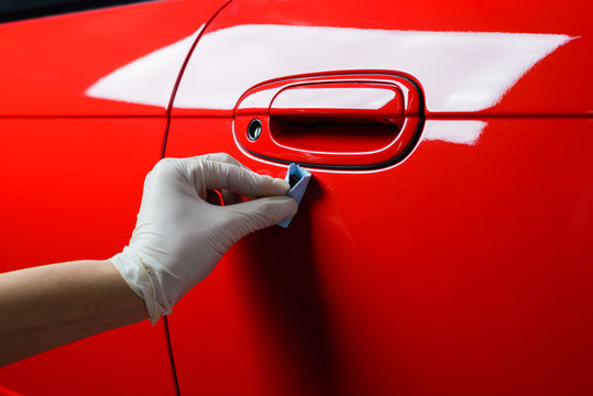 Fototapeta Car detailing series : Closeup of hand coating red car door