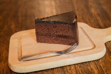 Close up Slice of chocolate cake with frok on wood table.