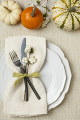 Fall autumn festive table setting place setting with pumpkins, plate, fork, knife and napkin on...