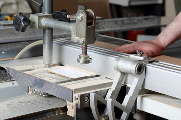 Carpenter cuts the board on rotating circular saw blade