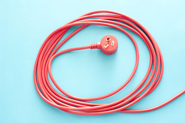 Coiled red electrical cable or lead with plug
