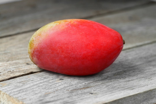 Red ripe mango fruit on wooden table closeup