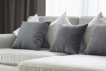 White and gray pillows setting on beige couch in living room