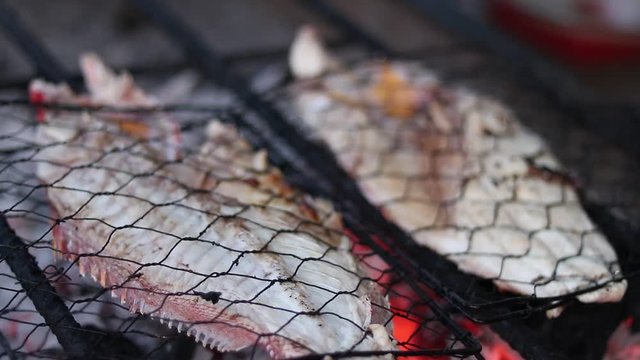 Fresh fish grilling on a charcoal barbecue outdoors, Bali, Indonesia. Cooking for a healthy nutritious family meal. Summer barbeque. 