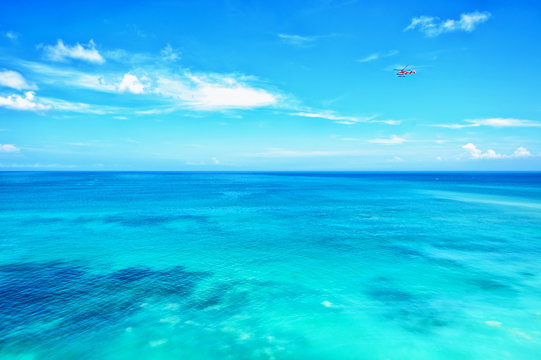 Fototapeta Small red helicopter in blue sky blue ocean horizon