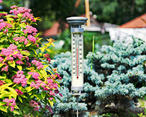 Modern stylish outdoor thermometer in summer garden. Closeup.
