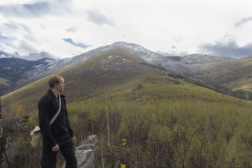 Naklejka premium Traveler in the mountains on the background of mountain landscape looking into the distance