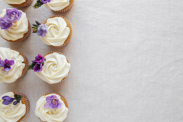 Rose flower frosting vanilla cupcakes with purple edible flowers