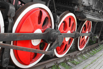 Tilted wheels of steam locomotive on rails closeup shot at an angle