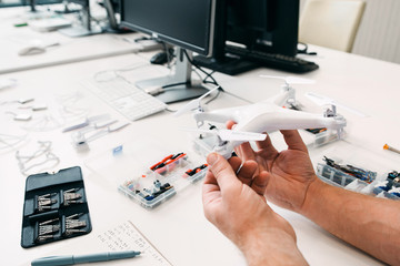 Close-up of drone in repairman hands, electronic toy repair shop. Electrician workplace with fixed...
