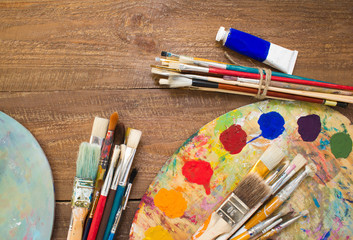 Fototapeta premium Paints, brushes and palette on the colorful background. The workplace of the artist. Banner for school