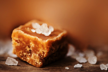 Caramel candy on brown  background macro. Salted caramel piece a