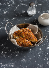 Quinoa crusted chicken in a metal bowl. On a dark background.