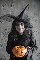 Halloween witch holding a pumpkin