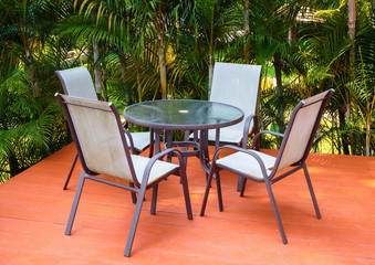 Table and chairs on the veranda in a tropical garden