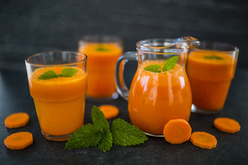 Fresh carrots and carrot juice on dark stone background. Healthy diet.