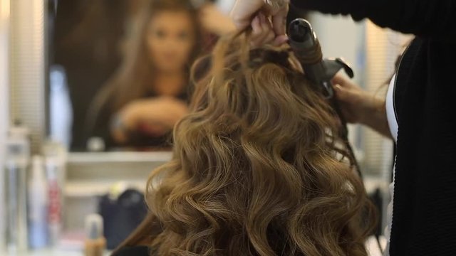 Hairdresser makes hairdress beautiful girl in a beauty salon
