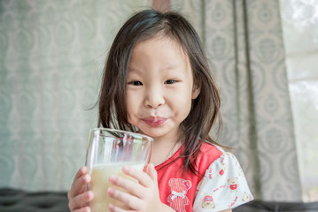 Little asian girl drinking milk from glass