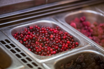 Close-up detail of cranberries, along with other berries, at a metal tray at a smoothie stand. Health and superfoods concept.